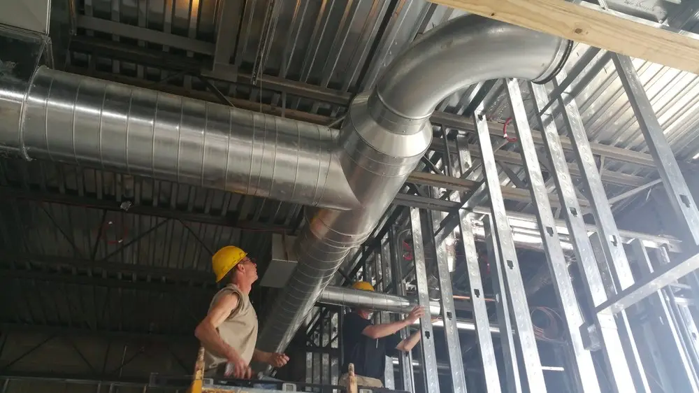 An HVAC contractor working on ductwork in a commercial heating, ventilation and air conditioning system.